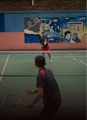 Pemain padel melakukan servis dengan latar mural di dinding lapangan